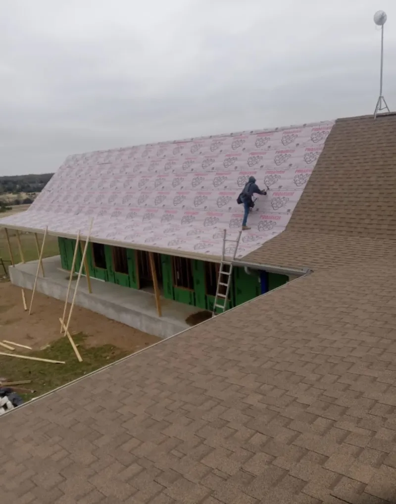 Worker preparing underlayment for a metal roof installation in Kahului